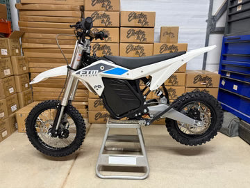 White and black dirt bike on a stand with boxes in the background