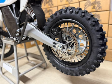 Close-up of a dirt bike wheel with a wooden wall background